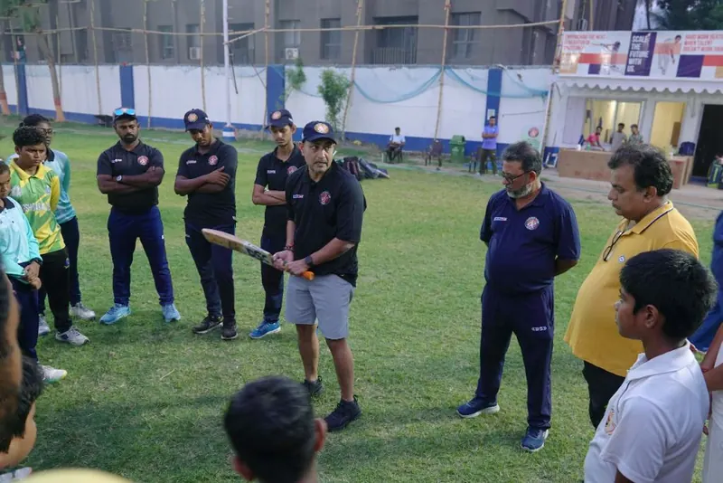 Deep Dasgupta demonstrating a batting grip to HHS coaches and players on the ground