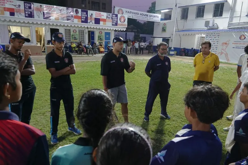 Deep Dasgupta addressing HHS coaches and players in a huddle on the ground
