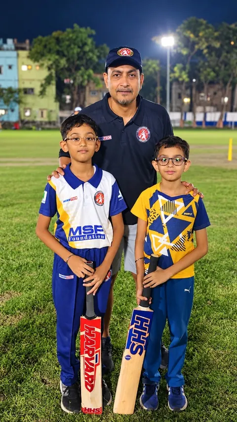 Deep Dasgupta, Mentor of Harvard House Sports, with two young HHS cricketers holding HHS bats under the floodlights