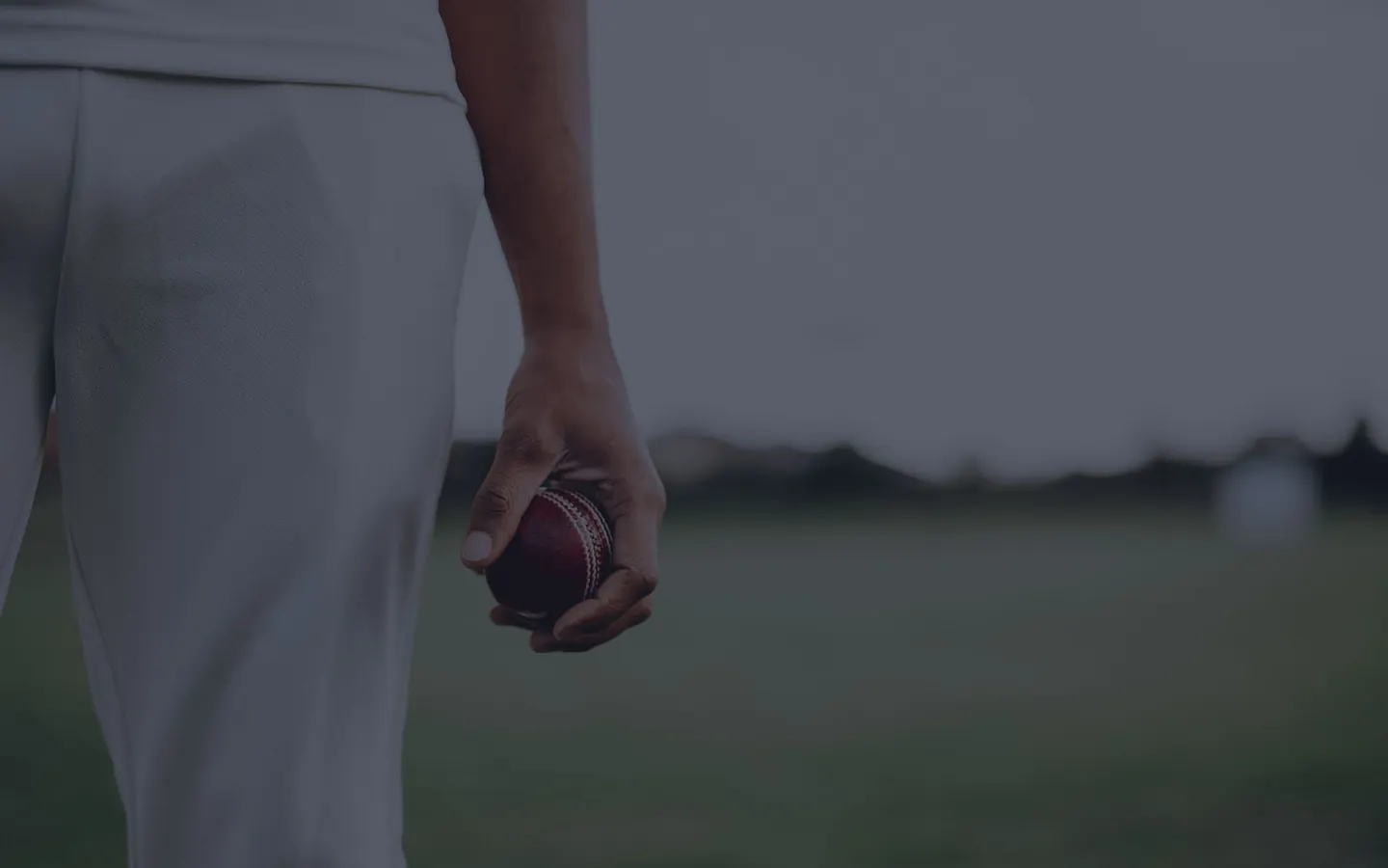 Bowler holding a red cricket ball